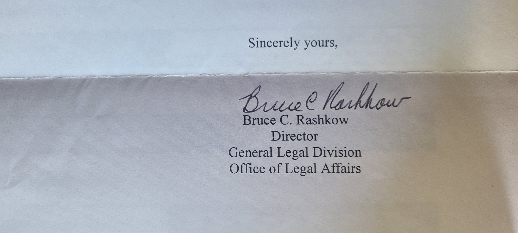 Photograph of a signed correspondence closing identifying Bruce C. Rashkow as Director, General Legal Division, Office of Legal Affairs.
